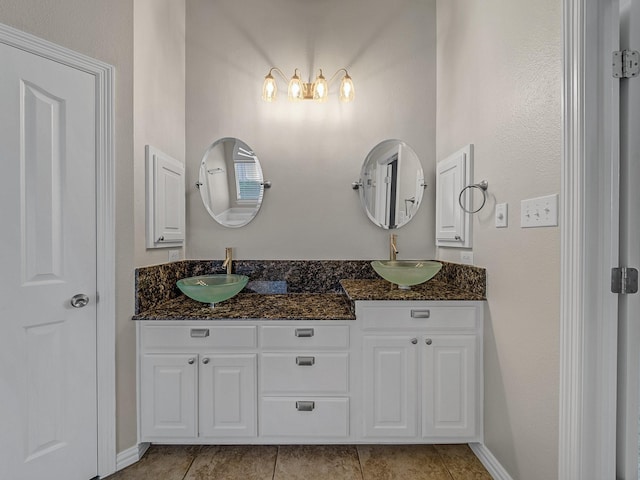 bathroom with double vanity, baseboards, and tile patterned floors