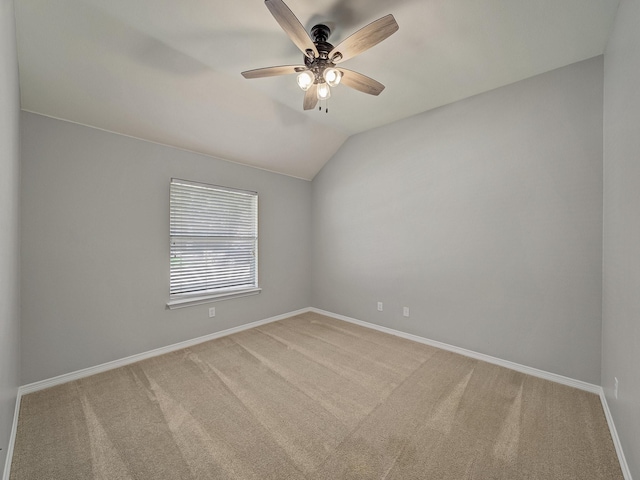 carpeted spare room featuring baseboards, lofted ceiling, and a ceiling fan