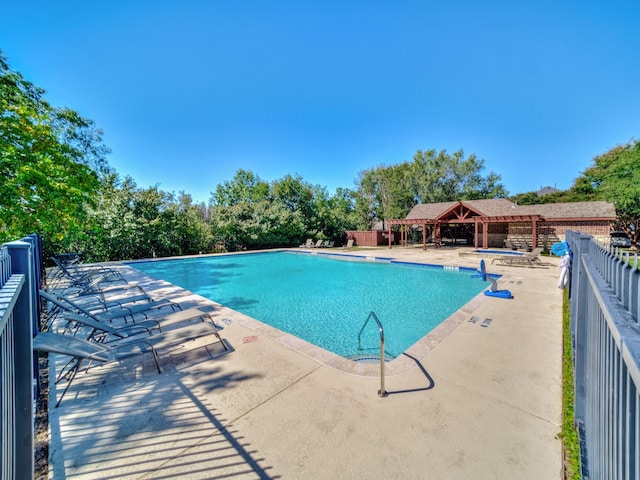 community pool with a gazebo, a patio, fence, and view of scattered trees