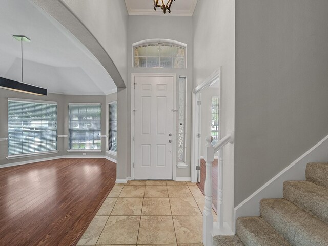 entrance foyer with crown molding, plenty of natural light, stairs, baseboards, and a high ceiling