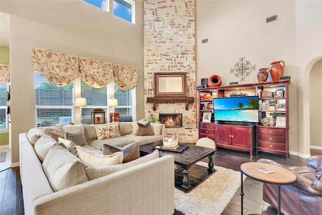 8205 Saint Clair Dr, Mckinney, TX 75071 - living room featuring a high ceiling, dark wood-style floors, baseboards, a large fireplace, and arched walkways