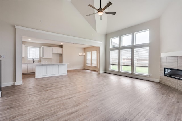 6725 Palmdale Dr, Fort Worth, TX 76123 - unfurnished living room featuring a tile fireplace, high vaulted ceiling, a ceiling fan, plenty of natural light, and light wood-style floors
