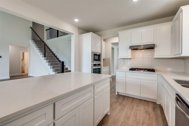 6725 Palmdale Dr, Fort Worth, TX 76123 - kitchen featuring appliances with stainless steel finishes, under cabinet range hood, light wood-type flooring, decorative backsplash, and recessed lighting