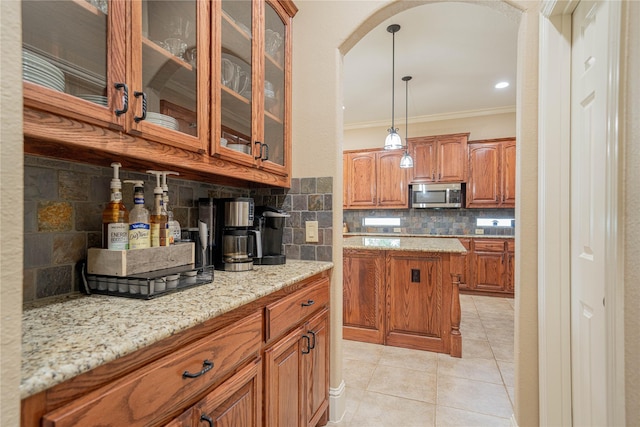 1020 High Meadow Dr, Mount Vernon, TX 75457 - kitchen featuring stainless steel microwave, arched walkways, crown molding, brown cabinets, and backsplash