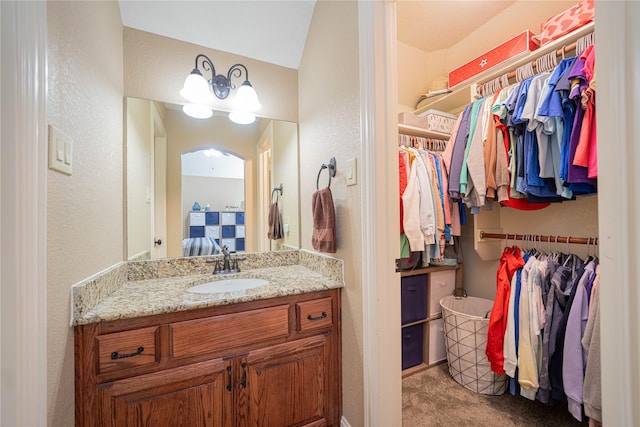 1020 High Meadow Dr, Mount Vernon, TX 75457 - bathroom featuring connected bathroom, a walk in closet, a textured wall, and vanity