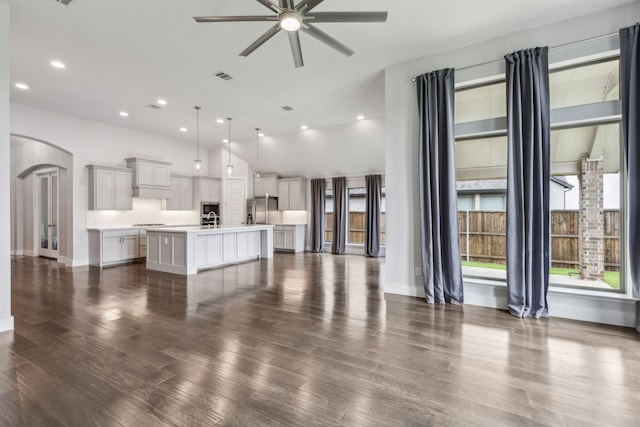 1108 Sandgate Dr, Forney, TX 75126 - unfurnished living room with arched walkways, a ceiling fan, recessed lighting, dark wood-style floors, and a sink