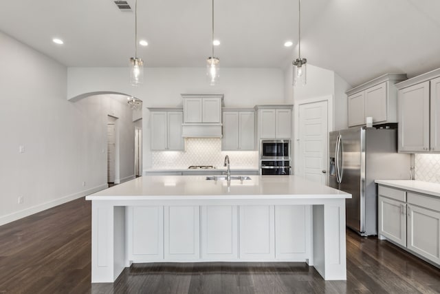 1108 Sandgate Dr, Forney, TX 75126 - kitchen with appliances with stainless steel finishes, arched walkways, backsplash, an island with sink, and light countertops