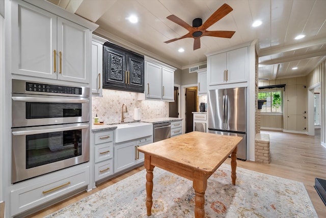 1111 Governors Dr, Corsicana, TX 75110 - kitchen with appliances with stainless steel finishes, a sink, a ceiling fan, tasteful backsplash, and light wood-style flooring