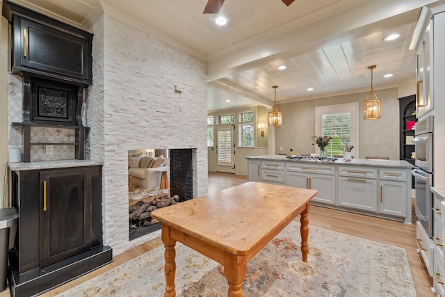 1111 Governors Dr, Corsicana, TX 75110 - kitchen featuring light wood-style flooring, a stone fireplace, ornamental molding, healthy amount of natural light, and white cabinetry