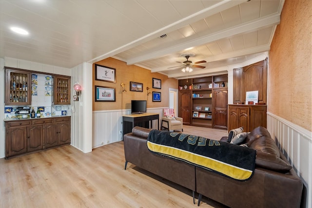 1111 Governors Dr, Corsicana, TX 75110 - living room featuring beamed ceiling, light wood-style flooring, a ceiling fan, wainscoting, and wooden ceiling