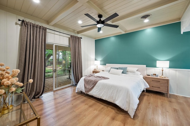 1111 Governors Dr, Corsicana, TX 75110 - bedroom featuring access to exterior, beamed ceiling, wood finished floors, a wainscoted wall, and a decorative wall