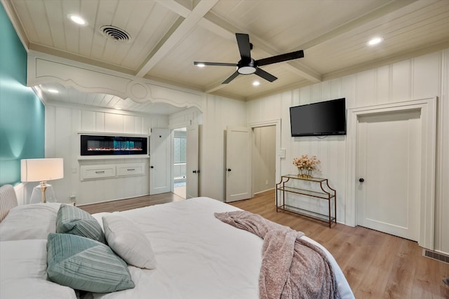 1111 Governors Dr, Corsicana, TX 75110 - bedroom with light wood-style floors, beamed ceiling, recessed lighting, a ceiling fan, and a glass covered fireplace