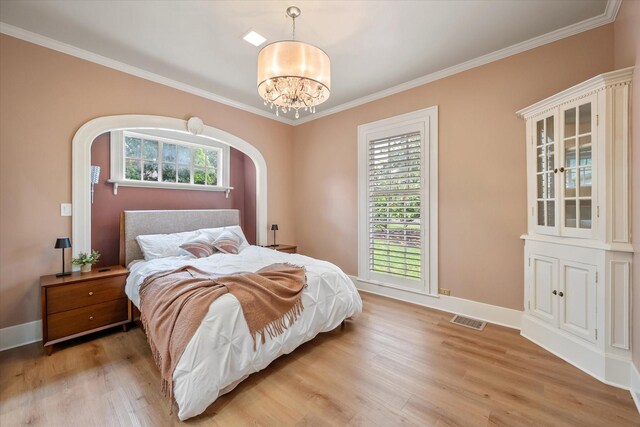 1111 Governors Dr, Corsicana, TX 75110 - bedroom with light wood-style floors, a chandelier, crown molding, baseboards, and arched walkways