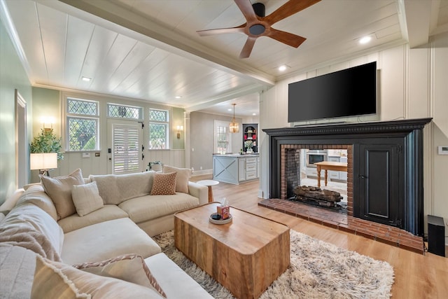 1111 Governors Dr, Corsicana, TX 75110 - living room with wood finished floors, a ceiling fan, a brick fireplace, ornamental molding, and beamed ceiling