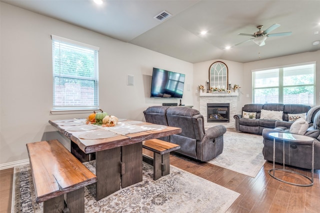 living area featuring wood finished floors, a ceiling fan, a stone fireplace, vaulted ceiling, and recessed lighting