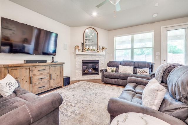 living area featuring healthy amount of natural light, a fireplace, ceiling fan, wood finished floors, and vaulted ceiling