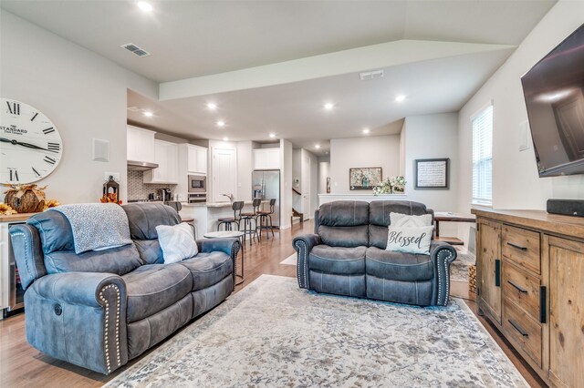 living area with light wood finished floors, recessed lighting, and vaulted ceiling