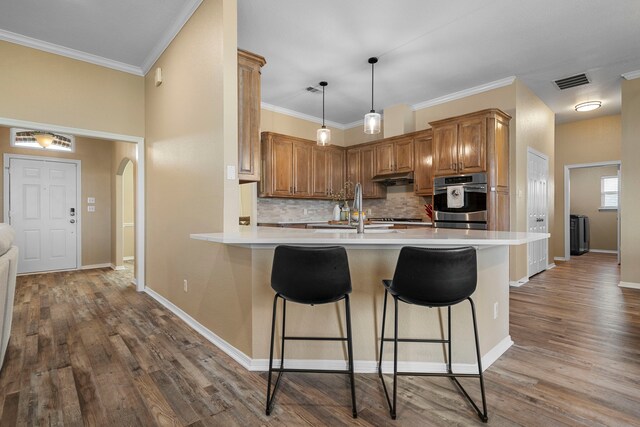 11448 Brook Green Ln, Haslet, TX 76052 - kitchen featuring oven, a sink, tasteful backsplash, a peninsula, and a kitchen bar