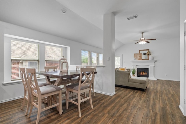 10149 Red Bluff Ln, Fort Worth, TX 76177 - dining space featuring dark wood-style flooring, vaulted ceiling, a glass covered fireplace, a ceiling fan, and baseboards