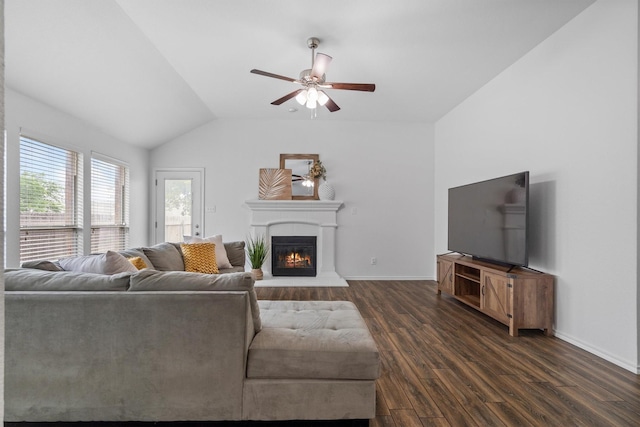 10149 Red Bluff Ln, Fort Worth, TX 76177 - living room featuring dark wood-type flooring, a glass covered fireplace, ceiling fan, vaulted ceiling, and baseboards