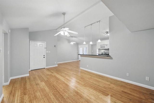 4620 Carr St, The Colony, TX 75056 - unfurnished living room featuring a ceiling fan, lofted ceiling, baseboards, light wood-type flooring, and rail lighting