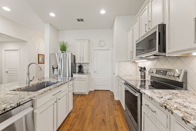 1316 Shinnecock Ct, Fairview, TX 75069 - kitchen featuring appliances with stainless steel finishes, a sink, light wood-style flooring, white cabinets, and decorative backsplash