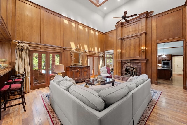 living area featuring a towering ceiling, a fireplace, light wood-style flooring, a ceiling fan, and recessed lighting