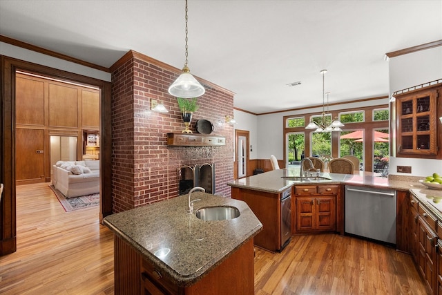 kitchen featuring stainless steel dishwasher, a brick fireplace, a sink, crown molding, and light wood-type flooring