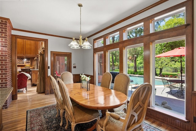 dining area with ornamental molding, light wood-style flooring, and a chandelier