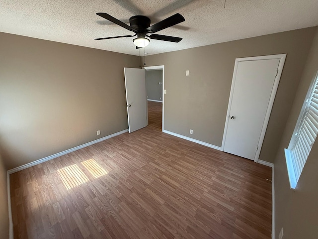 2325 S 40th St, Abilene, TX 79605 - unfurnished bedroom with wood finished floors, baseboards, a textured ceiling, and a ceiling fan