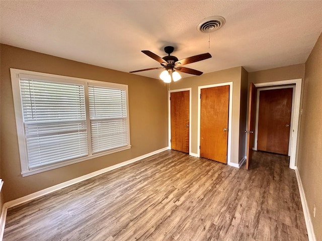 213 W Tennie St, Gainesville, TX 76240 - unfurnished bedroom with light wood-style floors, multiple closets, baseboards, a textured ceiling, and a ceiling fan