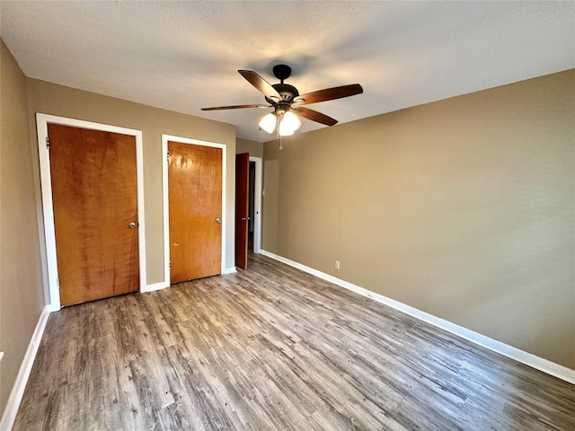 213 W Tennie St, Gainesville, TX 76240 - unfurnished bedroom with wood finished floors, multiple closets, baseboards, and ceiling fan