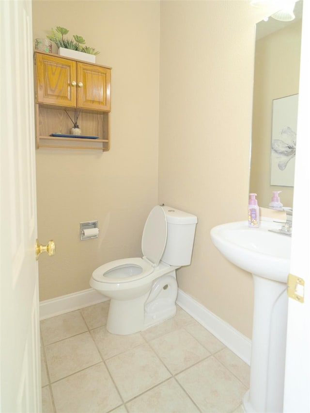 half bathroom with toilet, baseboards, and tile patterned flooring
