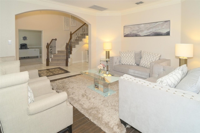 living room featuring arched walkways, stairs, crown molding, and wood finished floors