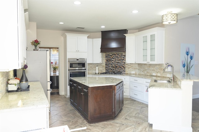 kitchen with a sink, custom exhaust hood, a peninsula, white cabinets, and recessed lighting