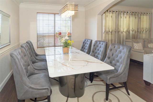 dining area featuring wood finished floors, crown molding, arched walkways, baseboards, and a chandelier