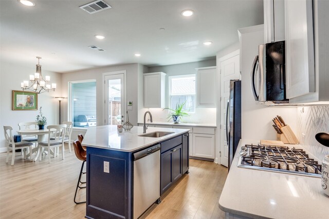 6628 Kort St, Rowlett, TX 75089 - kitchen featuring stainless steel appliances, a sink, light countertops, a kitchen bar, and white cabinetry