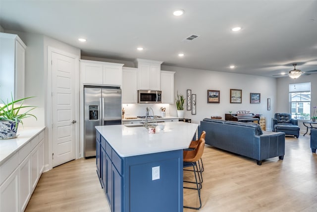 6628 Kort St, Rowlett, TX 75089 - kitchen with appliances with stainless steel finishes, open floor plan, a sink, light wood-type flooring, and white cabinets