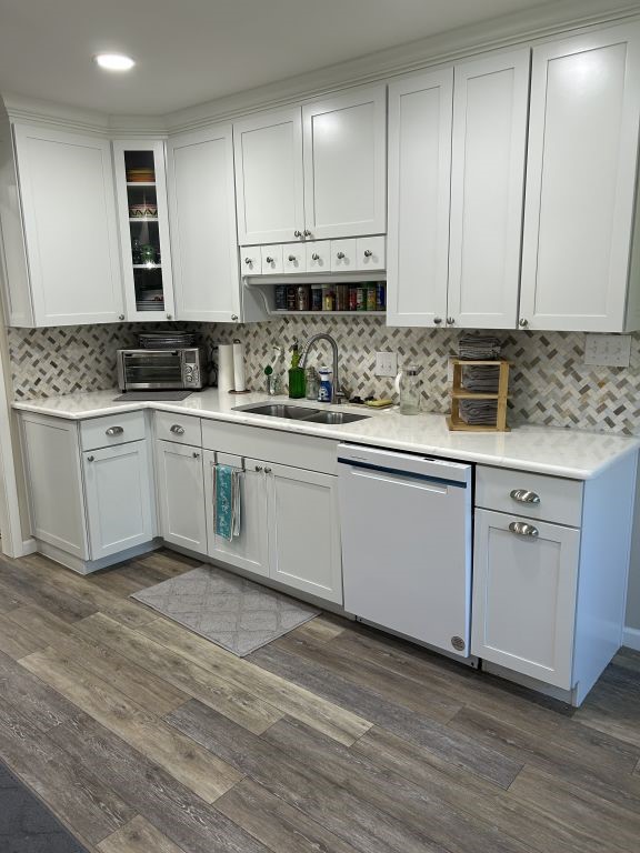 5004 Blackstone Dr, River Oaks, TX 76114 - kitchen with dishwashing machine, a sink, backsplash, light countertops, and dark wood-style flooring