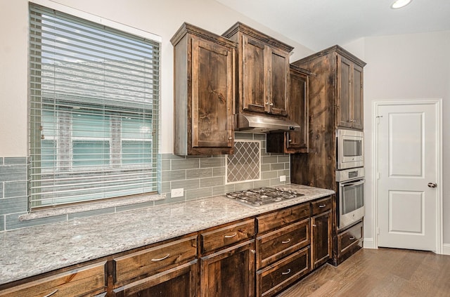 413 Allbright Rd, Celina, TX 75009 - kitchen with appliances with stainless steel finishes, under cabinet range hood, light stone counters, backsplash, and dark wood-style floors