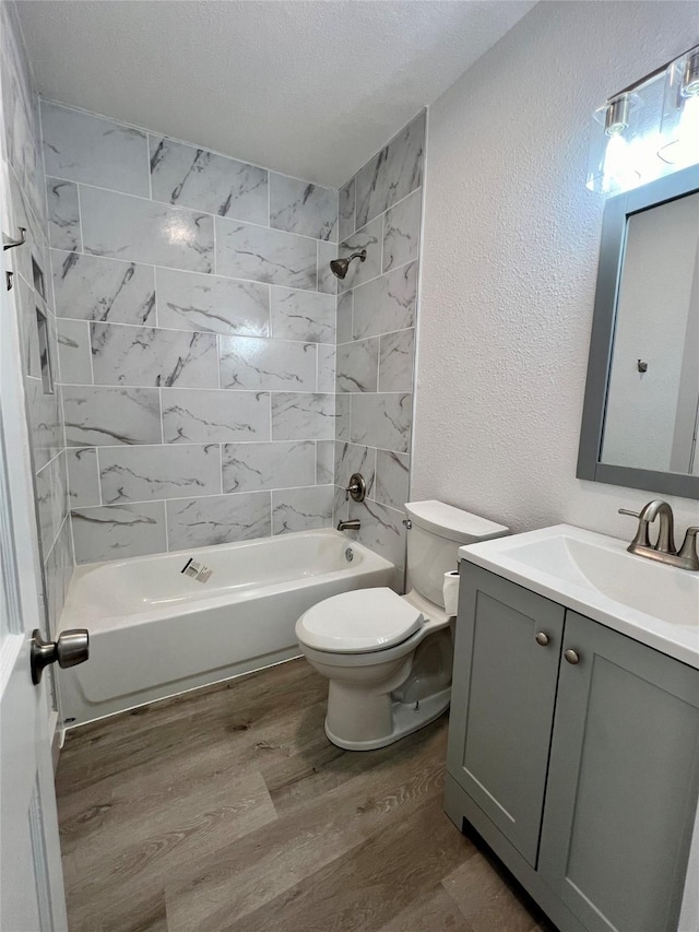 909 Hallum St, River Oaks, TX 76114 - full bath with wood finished floors, shower / bathtub combination, toilet, a textured wall, and vanity