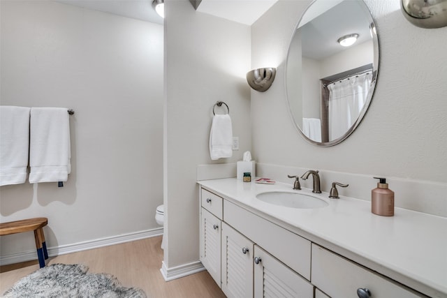 full bath with wood finished floors, vanity, toilet, and baseboards