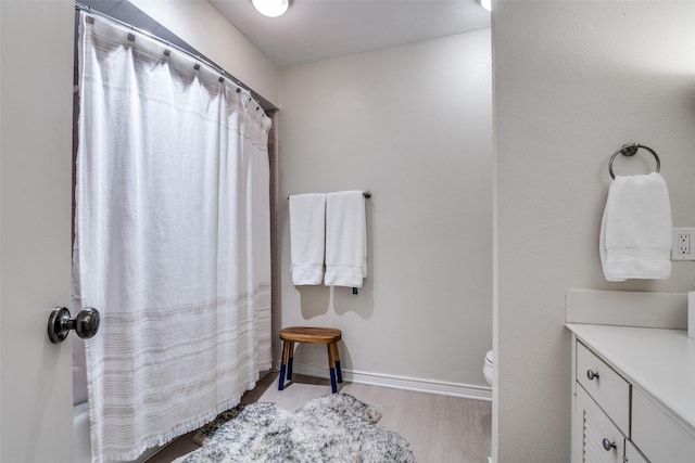 full bath featuring wood finished floors, toilet, baseboards, vanity, and shower / tub combo with curtain