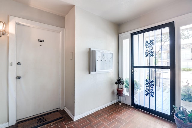 foyer entrance featuring baseboards, healthy amount of natural light, and brick patterned floors