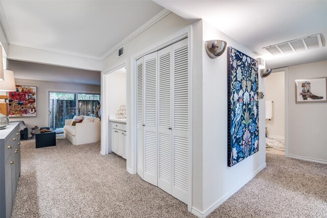 hallway with carpet flooring, crown molding, and baseboards