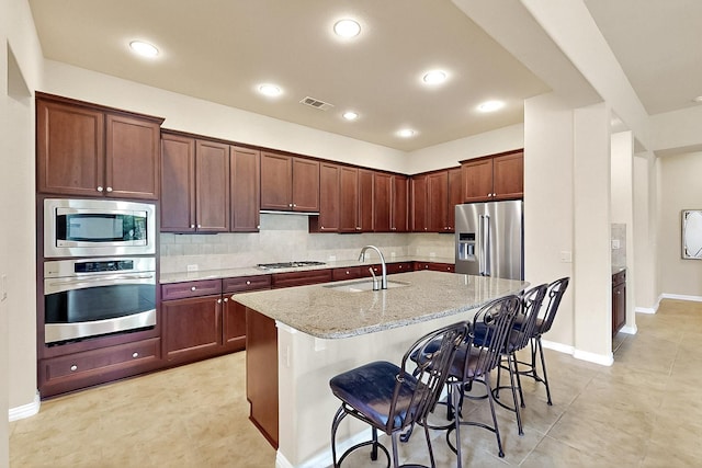 11908 Glenbrook St, Denton, TX 76207 - kitchen with appliances with stainless steel finishes, a sink, light stone countertops, a kitchen breakfast bar, and an island with sink