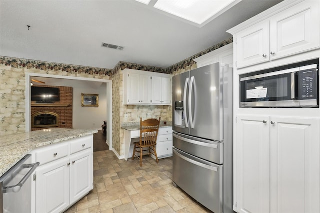 221 Valley Ranch Rd, Weatherford, TX 76087 - kitchen featuring stainless steel appliances, white cabinets, light stone finish flooring, and light stone countertops