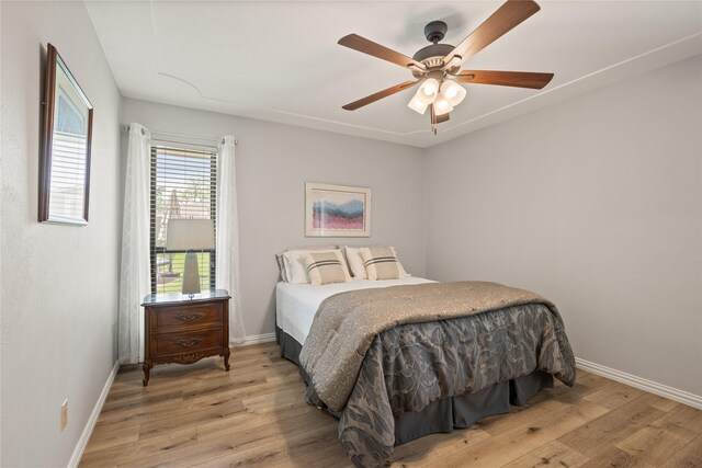 bedroom featuring wood finished floors, baseboards, and ceiling fan