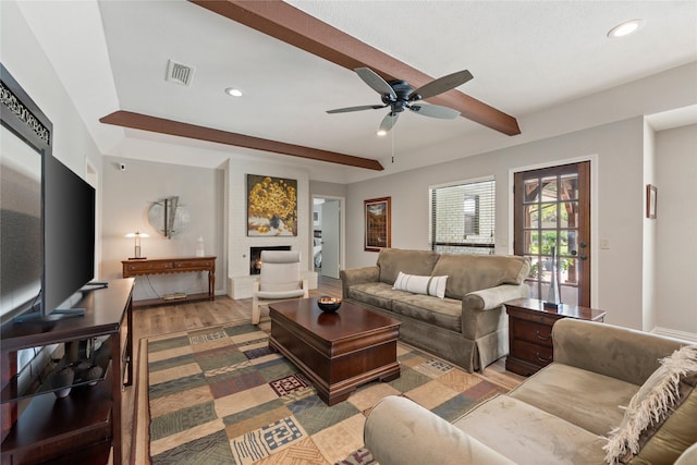 living area with recessed lighting, wood finished floors, a ceiling fan, beamed ceiling, and a large fireplace