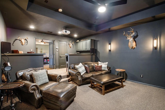 carpeted home theater room with ceiling fan, a raised ceiling, and baseboards